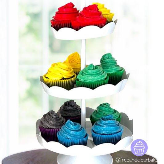 Three tiered cupcake stand containing chocolate cupcakes. Arranged in a descending rainbow with 2-3 cupcakes of each color, with matching frosting and cupcake liner