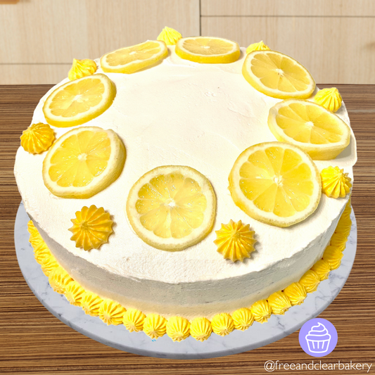 Lemon cake with white frosting and candied lemon slices in a circle, with yellow frosting dollop accents and border around the bottom