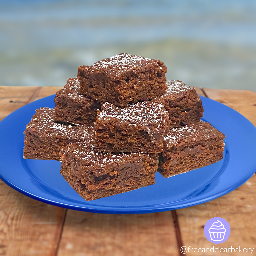 Blue plate with perfect brownies lightly sprinkled with powdered sugar, stacked in an askew pyramid