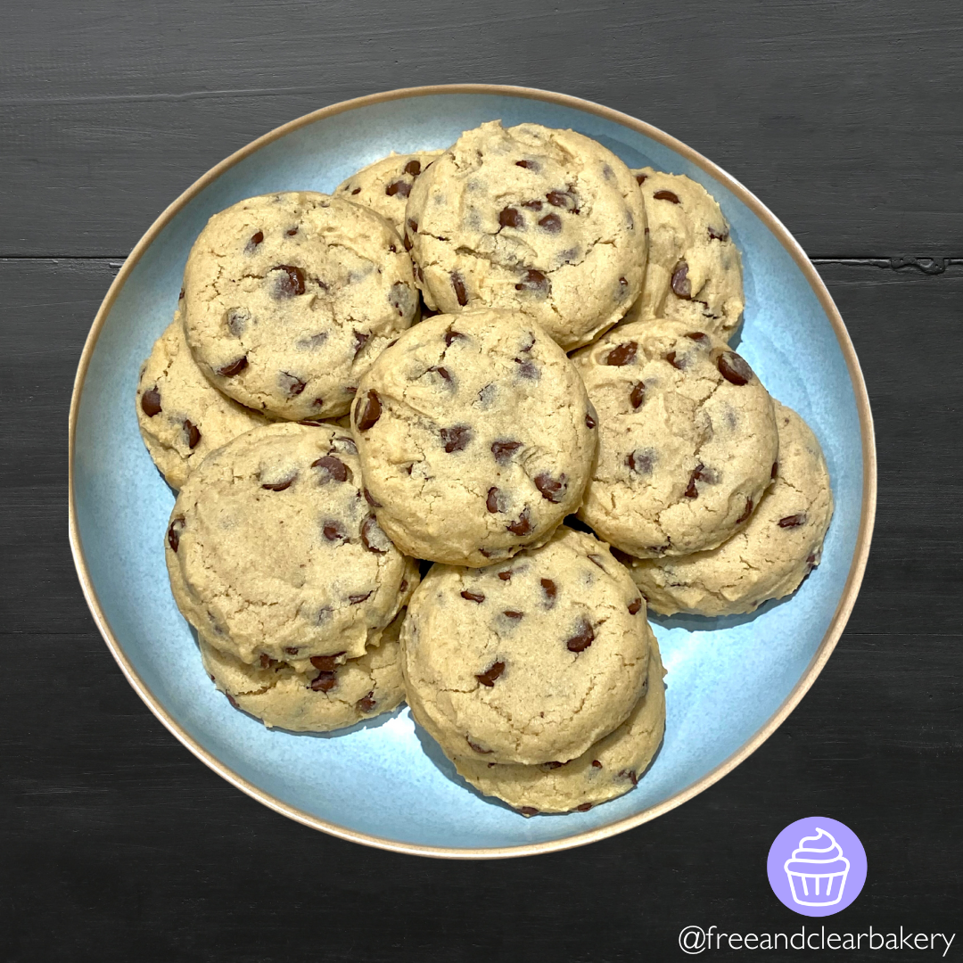 Overhead picture of a dozen jumbo chocolate chip cookies on a blue plate with gold rim.